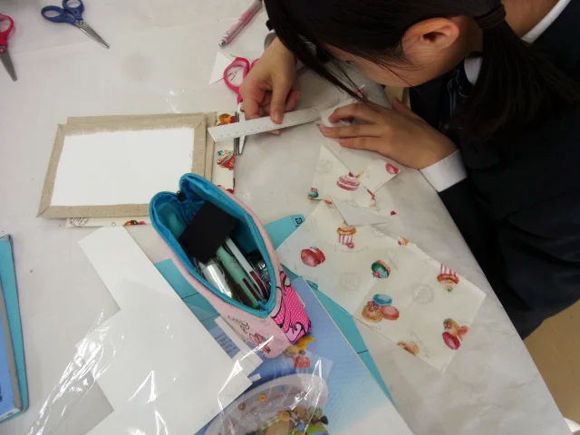 家庭科教材の導入事例:中学2年生の家庭科授業にてカルトナージュのノートカバーを約4時間かけて作成する生徒たちの様子:型紙を計る生徒の写真