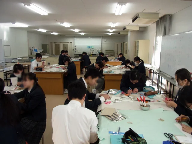 家庭科教材の導入事例：中学2年生の家庭科授業にてカルトナージュのノートカバーを約4時間かけて作成する生徒たちの様子：家庭科授業を受けるクラス全体の風景写真