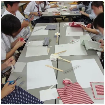 都内高等学校にて家庭科クラブ交流セミナーでカルトナージュ制作を実施した際の生徒達が型紙から作品を作り始めている様子の写真